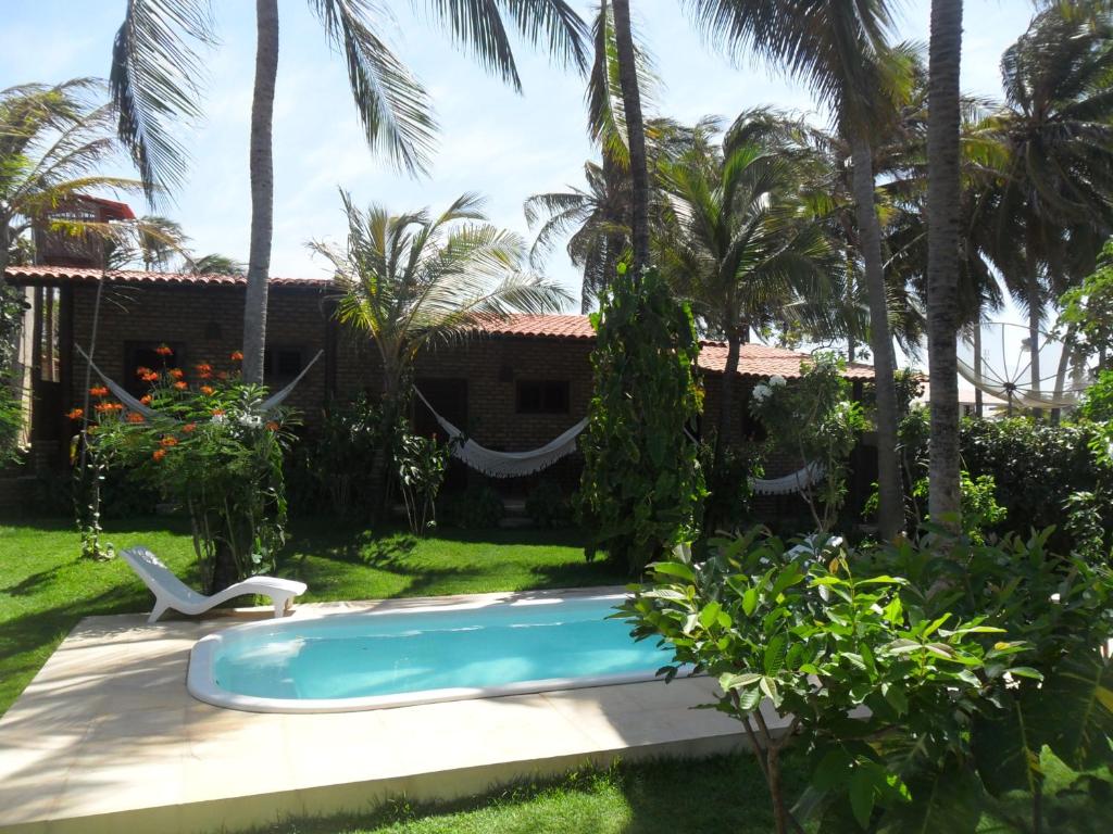 a swimming pool in front of a house with palm trees at Butterfly House in Flecheiras