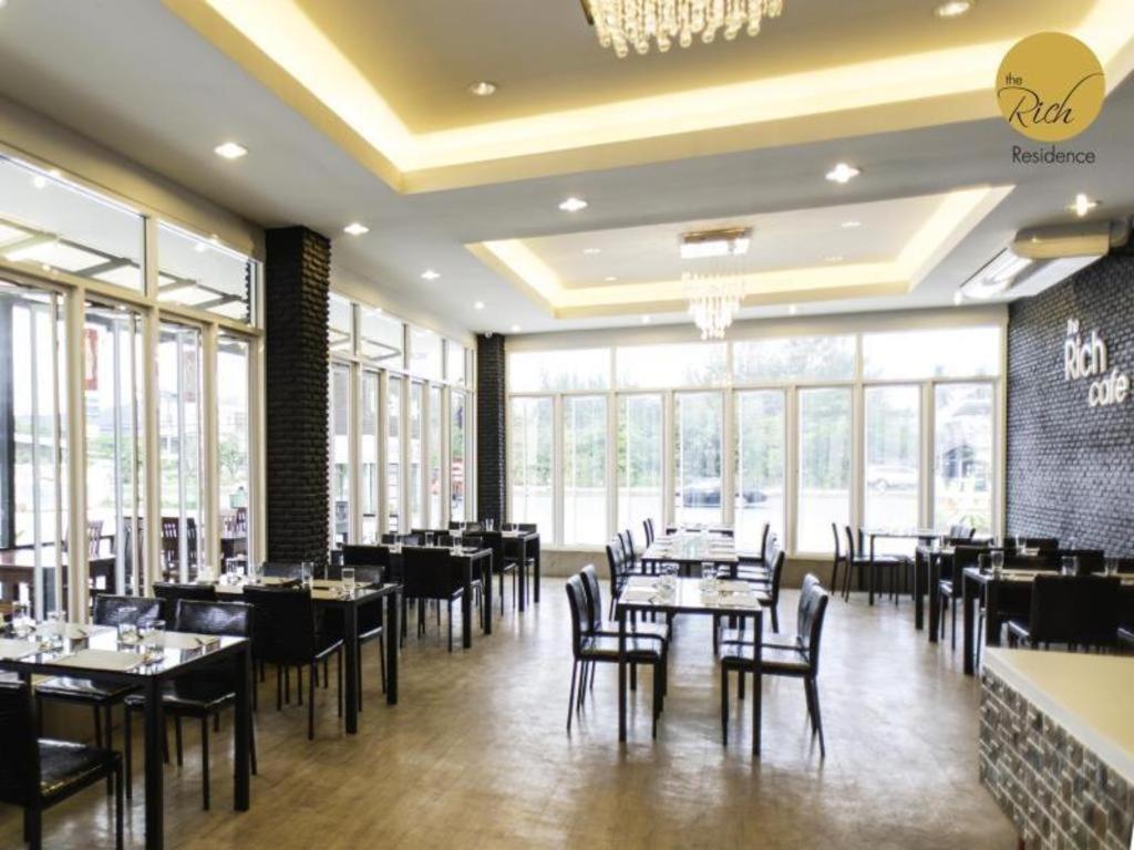 ein Esszimmer mit Tischen und Stühlen und Fenstern in der Unterkunft The Rich Residence in Ban Tha Kup