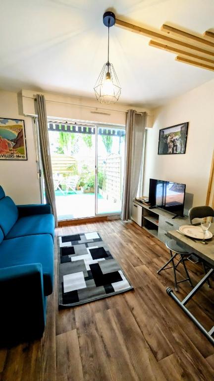 un salon avec un canapé bleu et une table dans l'établissement Le Petit Nid, T2 Rez de jardin avec parking - Plage et commerces à 15 à pied, à Villers-sur-Mer