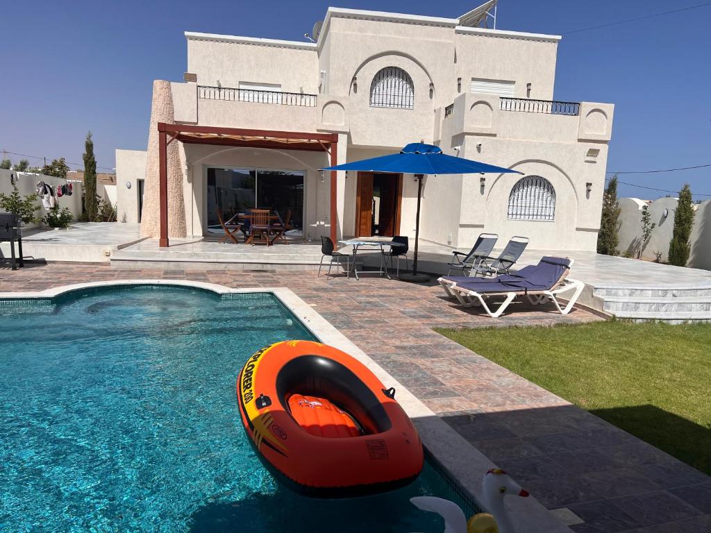 a house with a swimming pool with an orange tube in the water at VillaLina Haut Standing Djerba in Ajim