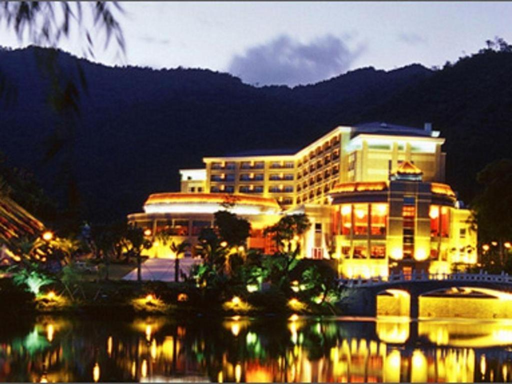 ein großes Gebäude mit nachts Licht auf dem Wasser in der Unterkunft The Lotus Villa Changan Dongguan in Dongguan