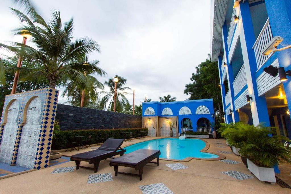 a blue building with a swimming pool next to a building at Pearl By The Sea Resort in Prachuap Khiri Khan
