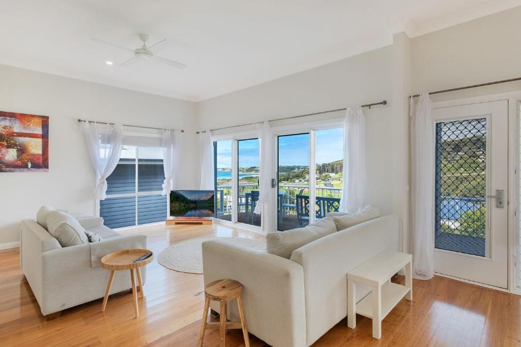 a living room with white furniture and a balcony at 8 Sunnyside Crescent Kianga in Kianga