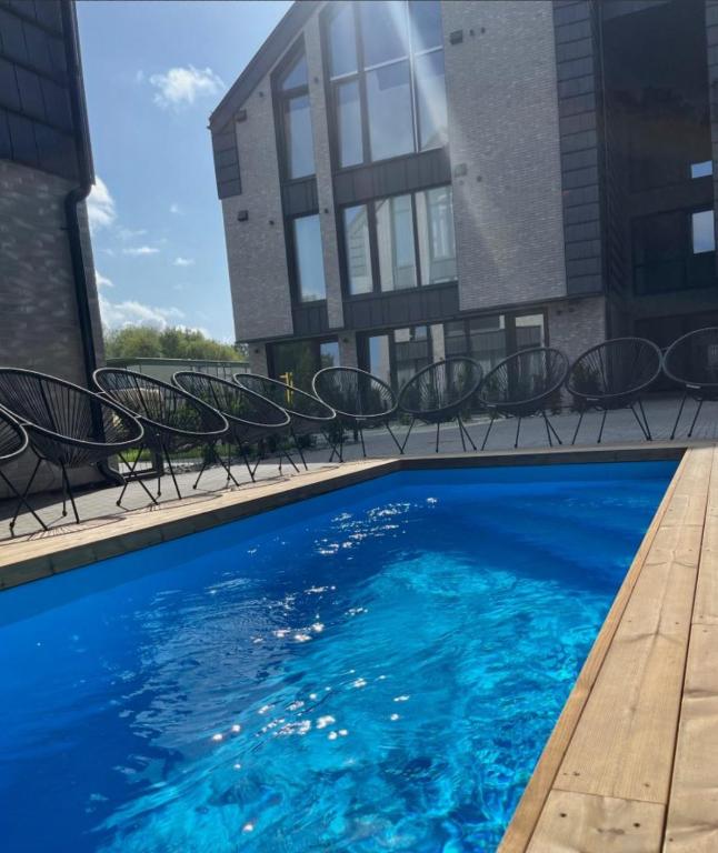 a swimming pool with chairs next to a building at Monciskes Apartment Seaside in Palanga