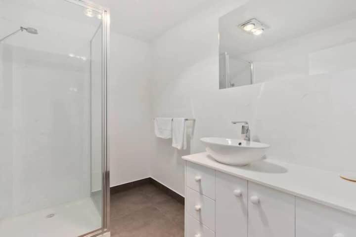 a white bathroom with a sink and a shower at Treetops-Large Home 9km to CBD Sleeps 10 in Hobart