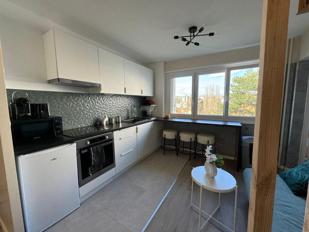 une cuisine avec des armoires blanches et une table avec des chaises dans l'établissement M49 Marquer T4 au calme secteur Brouaz, à Annemasse