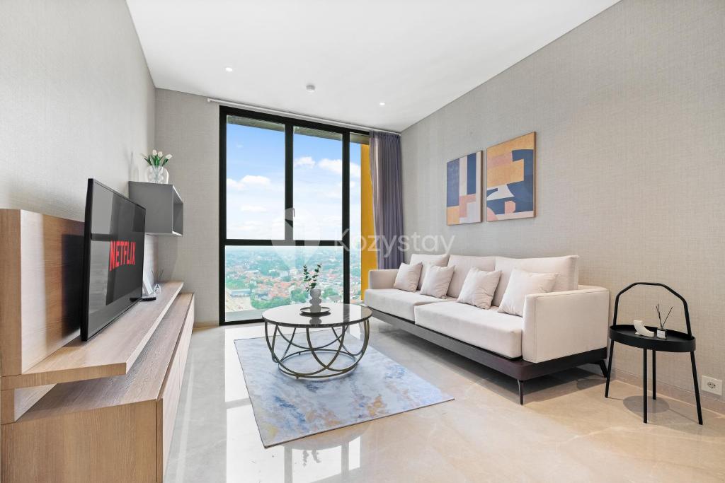 a living room with a white couch and a tv at Lumina by Kozystay - Cilandak in Jakarta