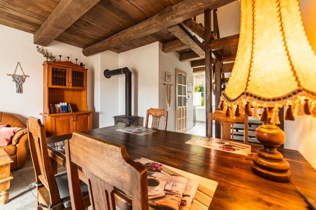 a dining room with a wooden table with a lamp at Chata Mazurska in Orzysz