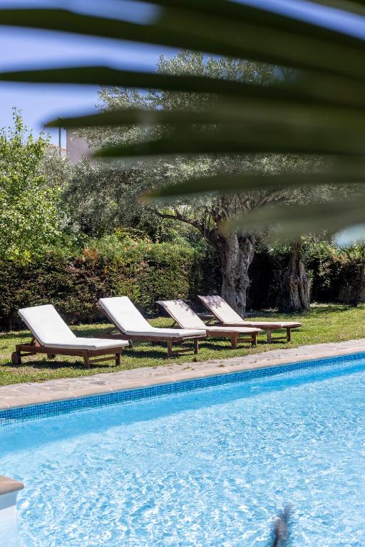 a row of lounge chairs next to a swimming pool at Felicia Dream House in Kamena Vourla