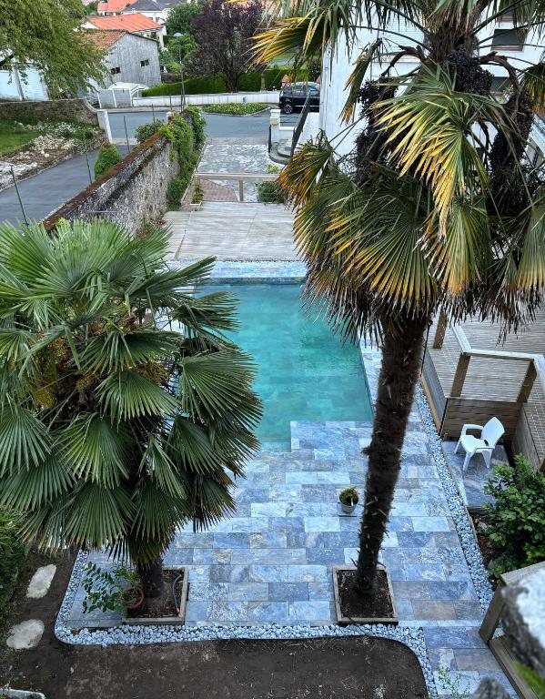 - une piscine bordée de palmiers dans une cour dans l'établissement La Mine des 4 pierres, aux Épesses