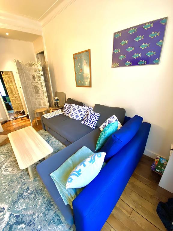 - un salon avec un canapé bleu et des oreillers dans l'établissement Near Paris, charming quiet sunny 2 rooms, à Pantin