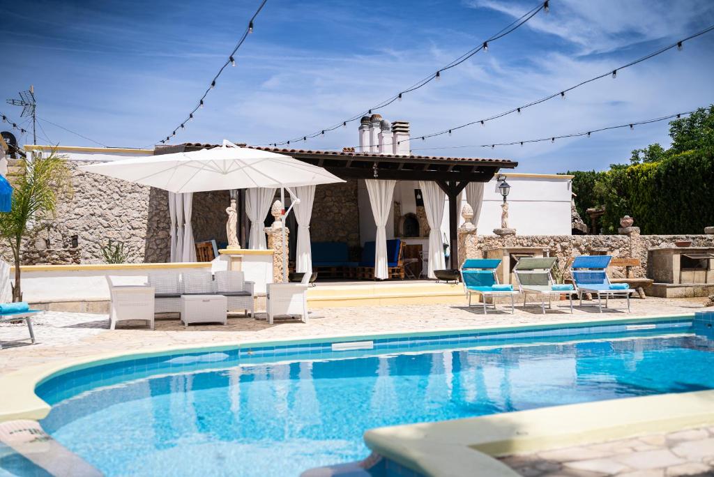 a swimming pool with chairs and an umbrella at Villa Vinne Cirase in Castiglione dʼOtranto