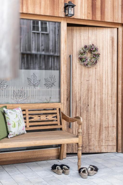 a wooden bench sitting in front of a door at Ferienwohnungen am Dorfbach in Bezau