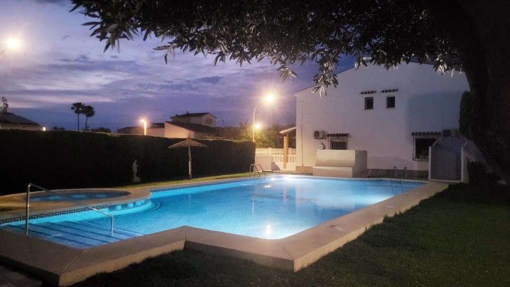a swimming pool in front of a house at night at La Casita Denia, charming 2BR Townhouse with shared Pool, 1km to Beach in Els Poblets