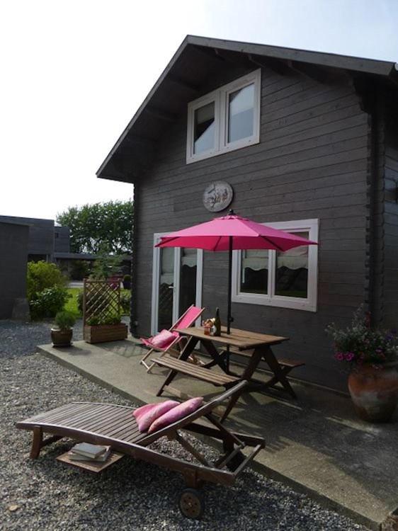 une table de pique-nique avec deux chaises et un parasol rose dans l'établissement La voile blanche, à Berneval-le-Grand