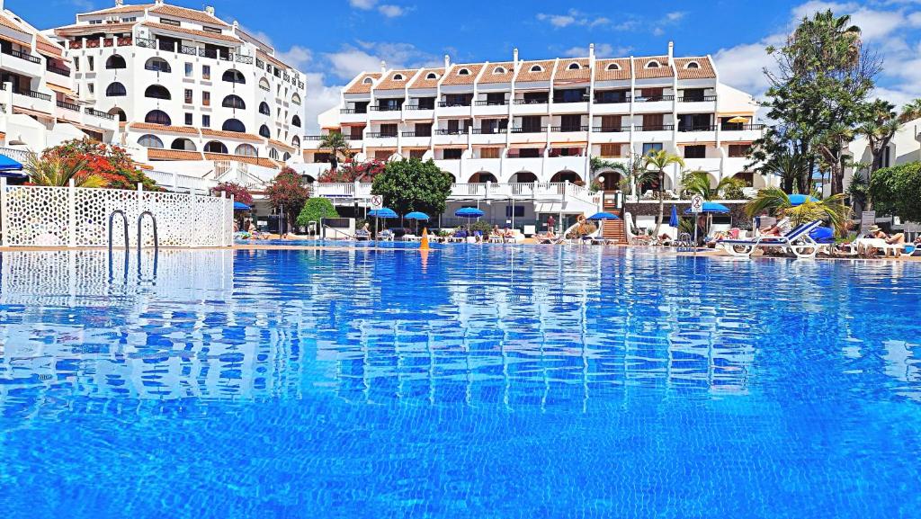 a large swimming pool with blue water in a resort at Parque Santiago II - Air Conditioning - Ocean View - 350mt from the beach in Playa de las Americas