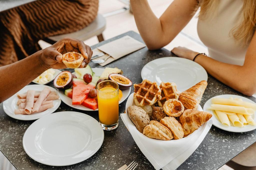 a group of people sitting at a table with breakfast foods at Aqua Pedra Dos Bicos Design Beach Hotel - Adults Friendly in Albufeira