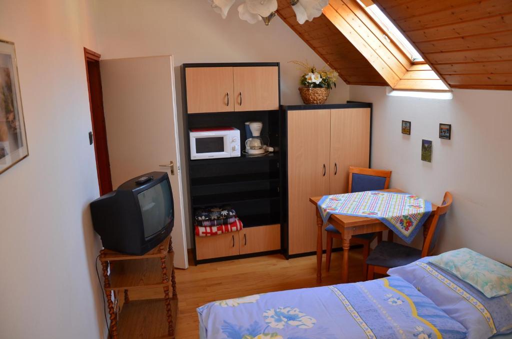 sypialnia z łóżkiem, telewizorem i stołem w obiekcie Orchidea Apartman w Hévízie