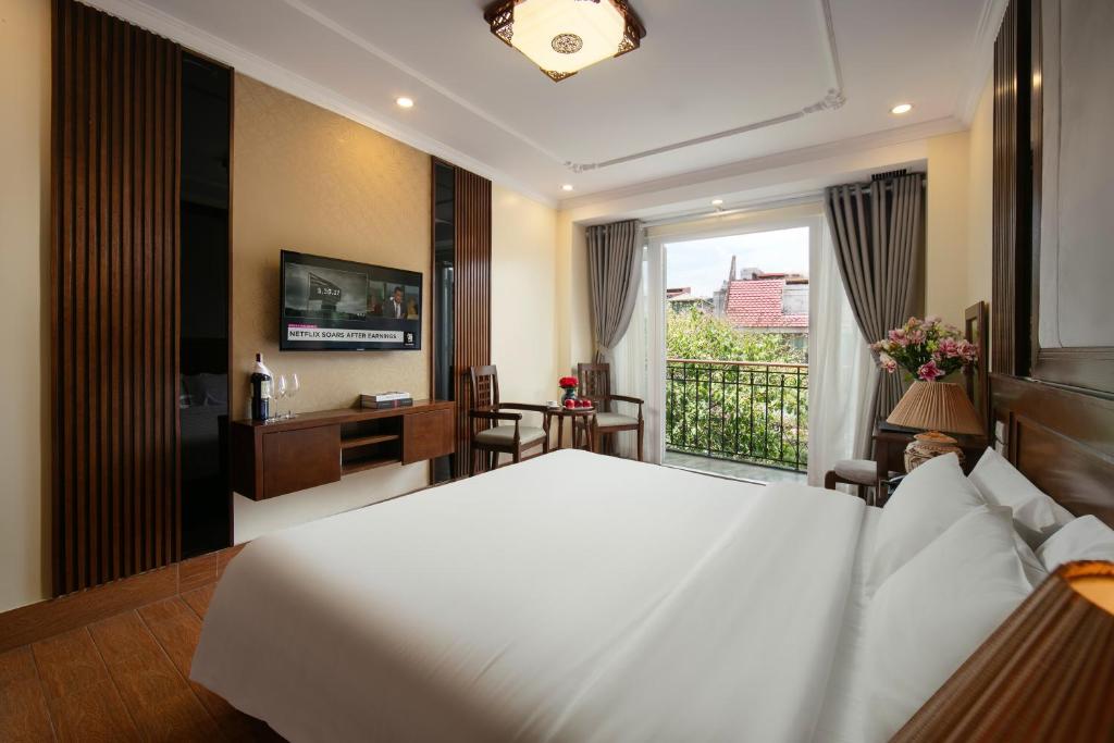 a bedroom with a large white bed and a balcony at The West Hotel & Spa in Hanoi
