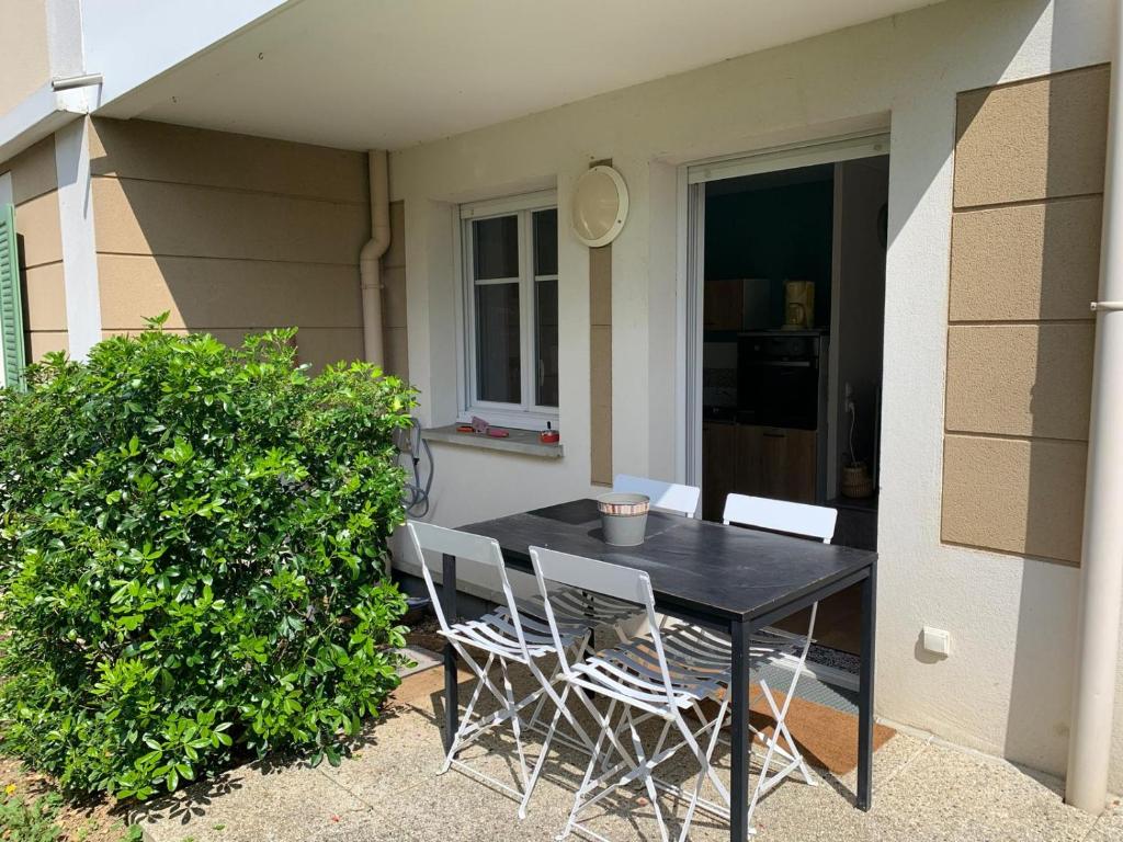 une table et des chaises noires devant une maison dans l'établissement Paris Saclay Versailles à 20 minutes, à Nozay