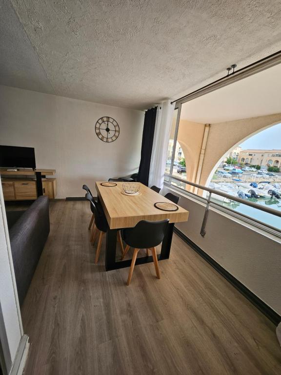 une salle à manger avec une table, des chaises et une horloge dans l'établissement studio cabine - Sète - 6personnes - rénové - moderne - en bord de plage avec clim, à Sète