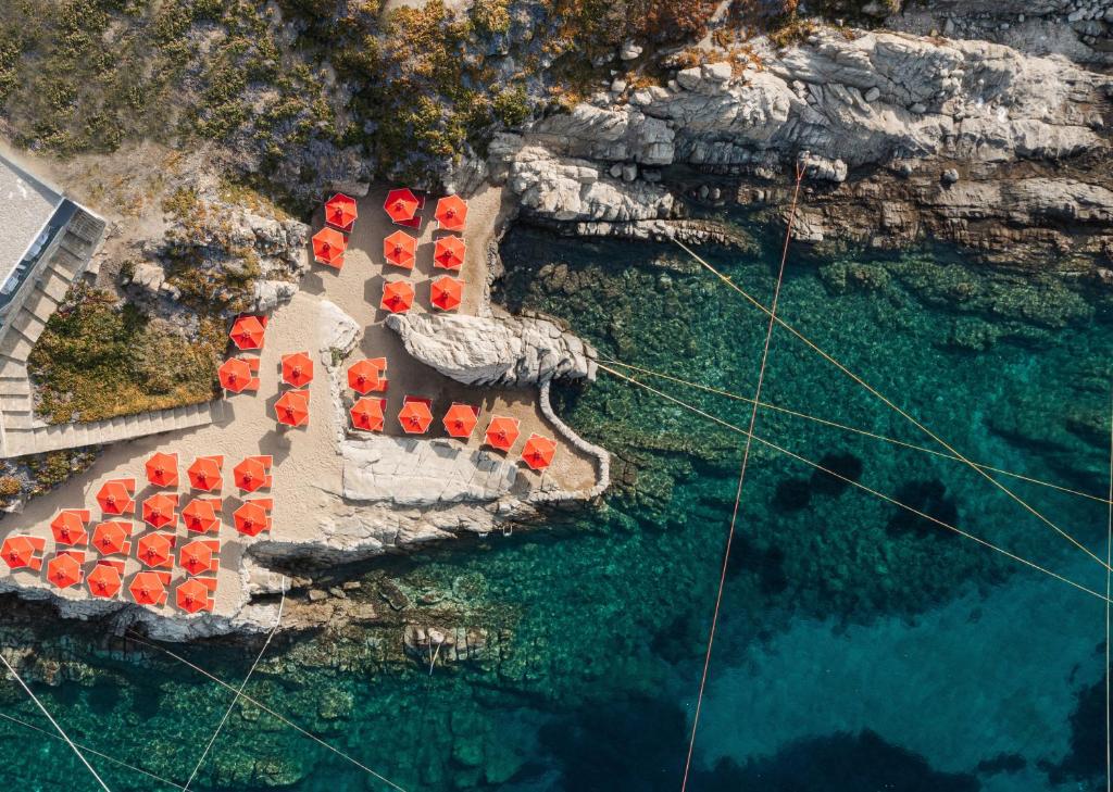 an overhead view of a bunch of red chairs in the water at Petasos Beach Resort & Spa - Small Luxury Hotels of the World in Platis Yialos Mykonos