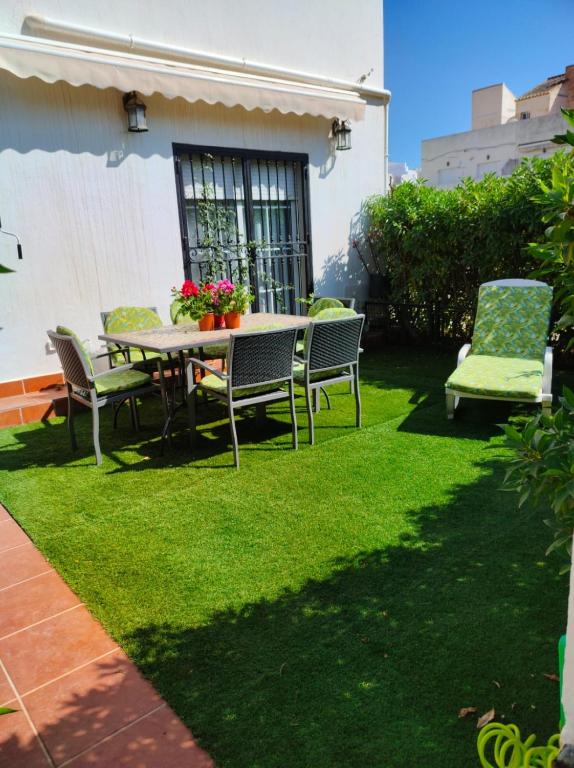 a patio with a table and chairs on the grass at Dúplex Buganvillas in Los Amarguillos