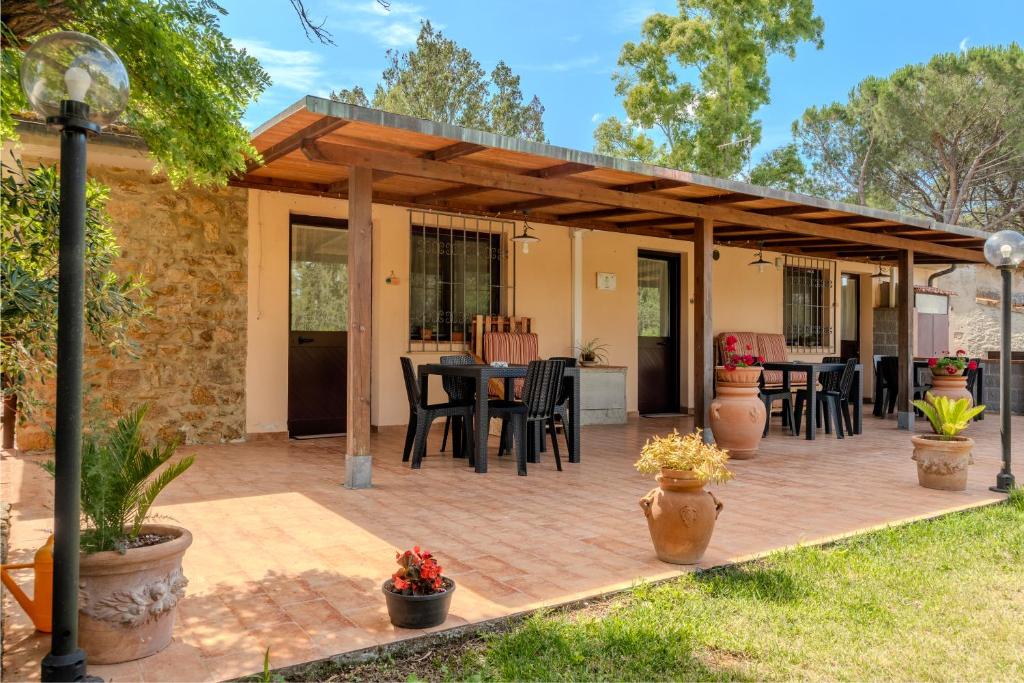 a patio with chairs and tables and a wooden pergola at Agriturismo Il Cipresso in Forni di Gavorrano