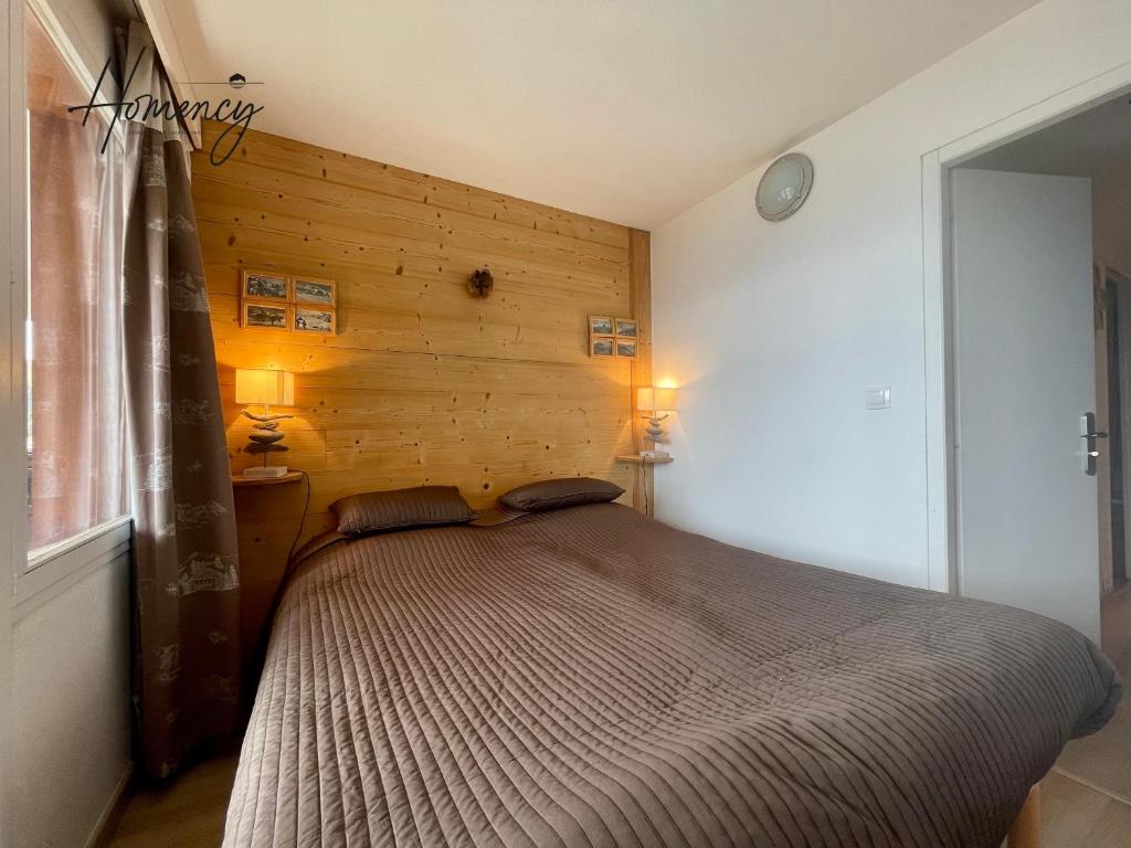 Ce lit se trouve dans une chambre dotée d'un mur en bois. dans l'établissement Homency - Résidence L'Ours Blanc 852, à L'Alpe-d'Huez