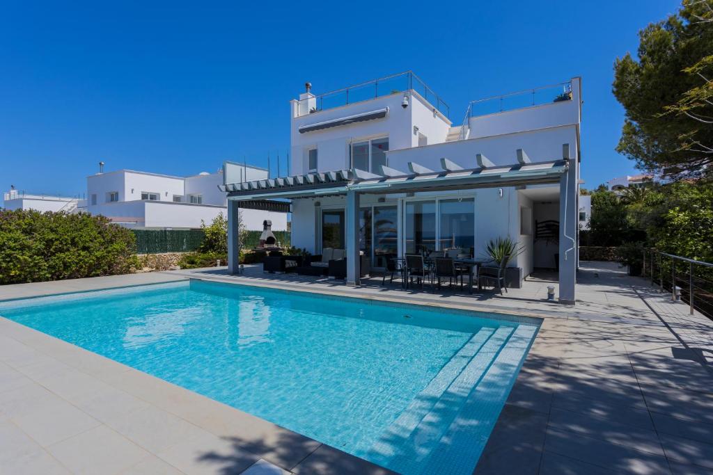 una villa con piscina frente a una casa en V196 Villa Brisa by Menorcarentals Villas, en Son Bou