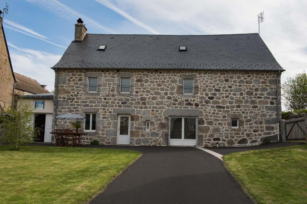 a large stone house with a driveway in front of it at Gites de france 3 epis 8 personnes a malbouzon in Malbouzon