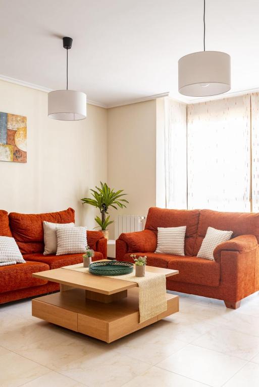 a living room with two orange couches and a coffee table at Apartamento en Badames con piscina comunitario in Bádames