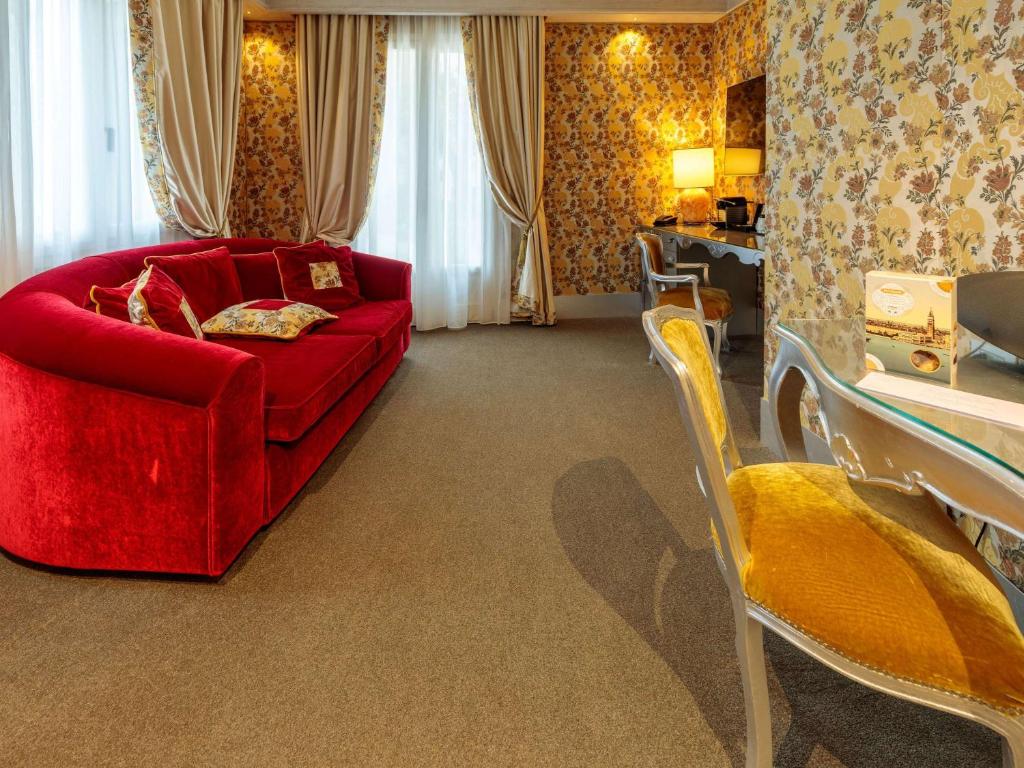 a living room with a red couch and chairs at Papadopoli Hotel Venezia - MGallery Collection in Venice