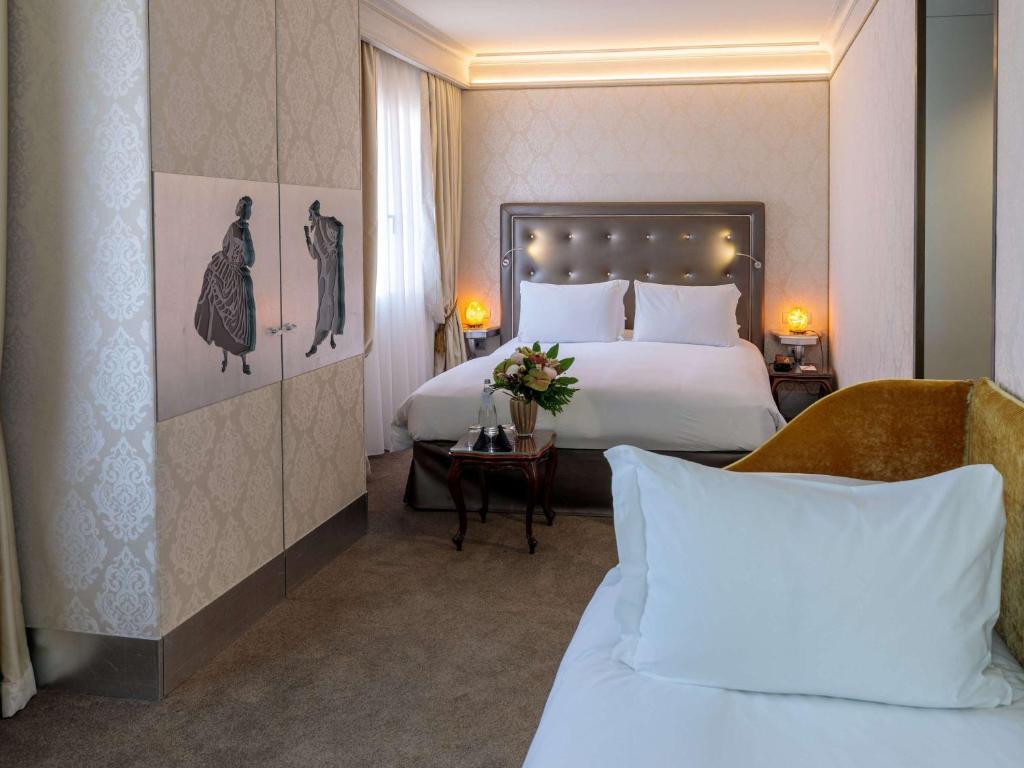 a hotel room with two beds with white pillows at Papadopoli Hotel Venezia - MGallery Collection in Venice