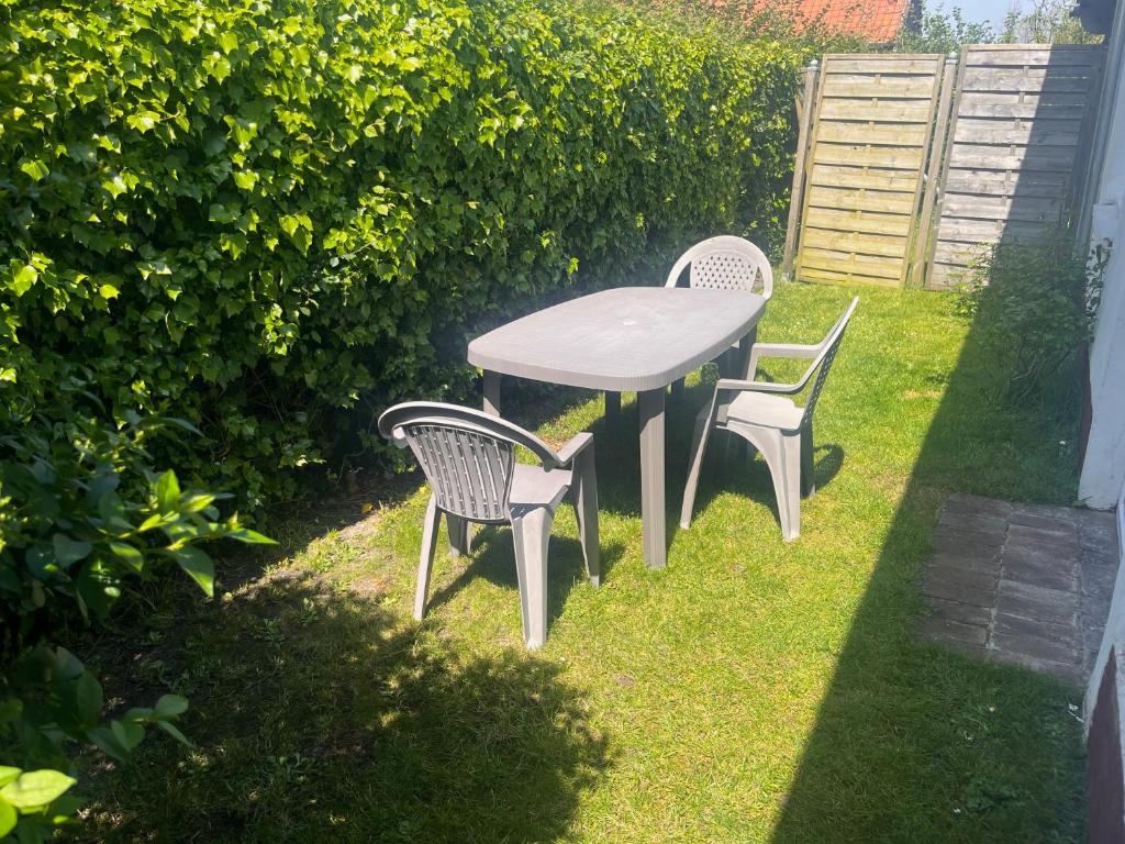 a table and two chairs sitting in the grass at Petite maison à la mer in Fort-Mahon-Plage