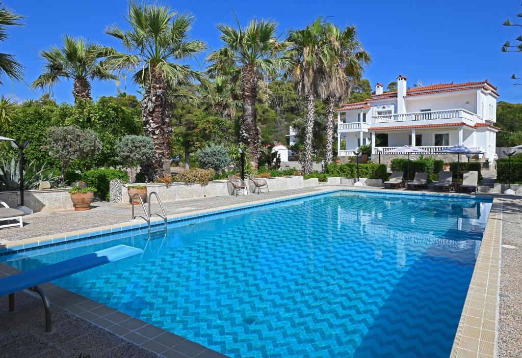 a swimming pool in front of a house with palm trees at Villa Supreme in Kato Alepochori