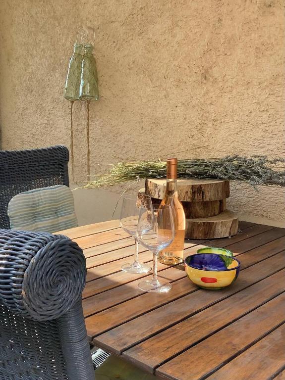 - une table en bois avec 2 verres à vin et une bouteille dans l'établissement Rdc de ma maison dans un joli village Provençal, 15 mins d'Aix en Pce, open space joliment rénové, à Fuveau