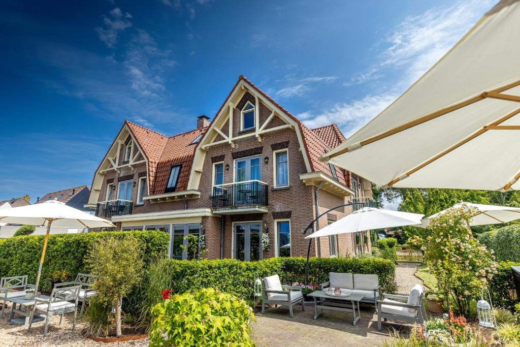 a house with chairs and umbrellas in front of it at Hotel Villa Vida in Domburg