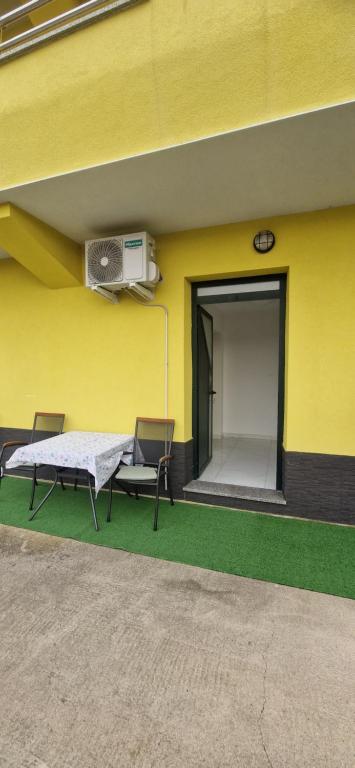 瓦比尼科Sunce 4的一栋带有露台的建筑，露台上配有两把椅子和一台风扇