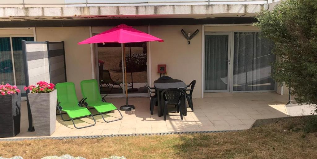 un patio avec une table, des chaises et un parasol dans l'établissement Comfortable nest just a stone's throw from the sea, au Pouliguen