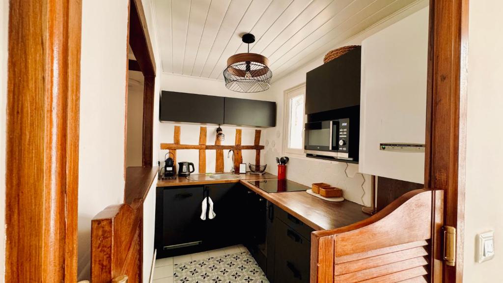 a kitchen with black cabinets and a wooden counter top at Charmant T2 en coeur de ville 15min de Disney in Lagny