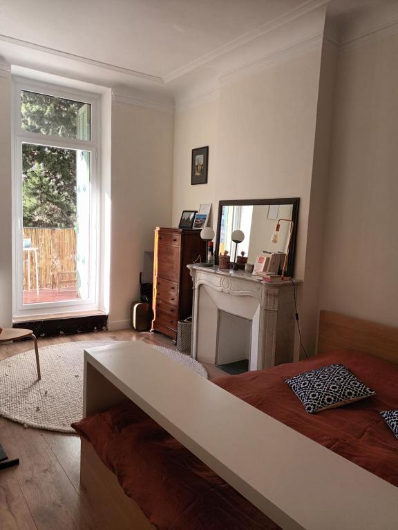 - une chambre avec un lit, une cheminée et une fenêtre dans l'établissement Grand T3 Breteuil, à Marseille