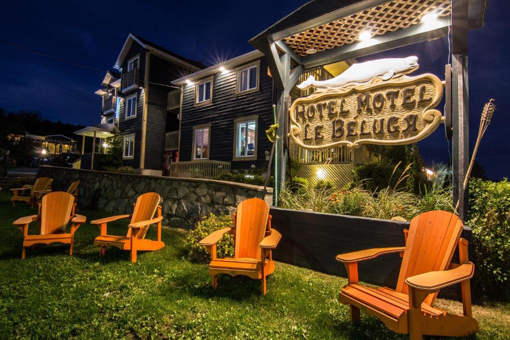 un groupe de chaises devant une maison avec un panneau dans l'établissement Hôtel Motel Le Beluga, à Tadoussac