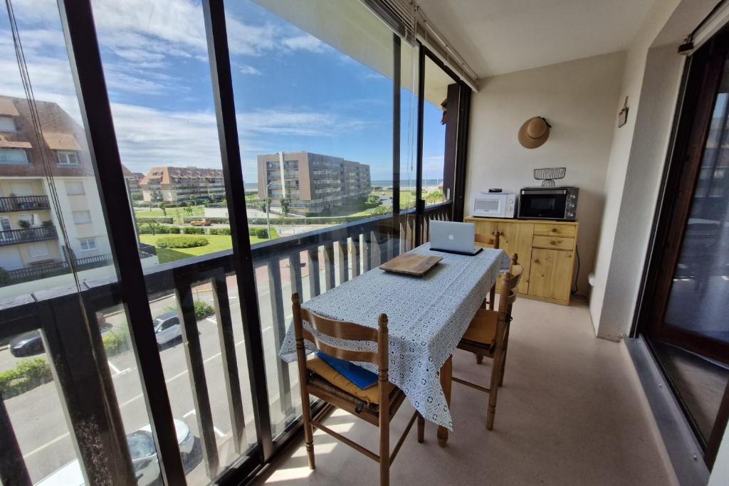 une cuisine avec une table et un ordinateur portable sur un balcon dans l'établissement Comfortable two-room nest with sea view, à Villers-sur-Mer