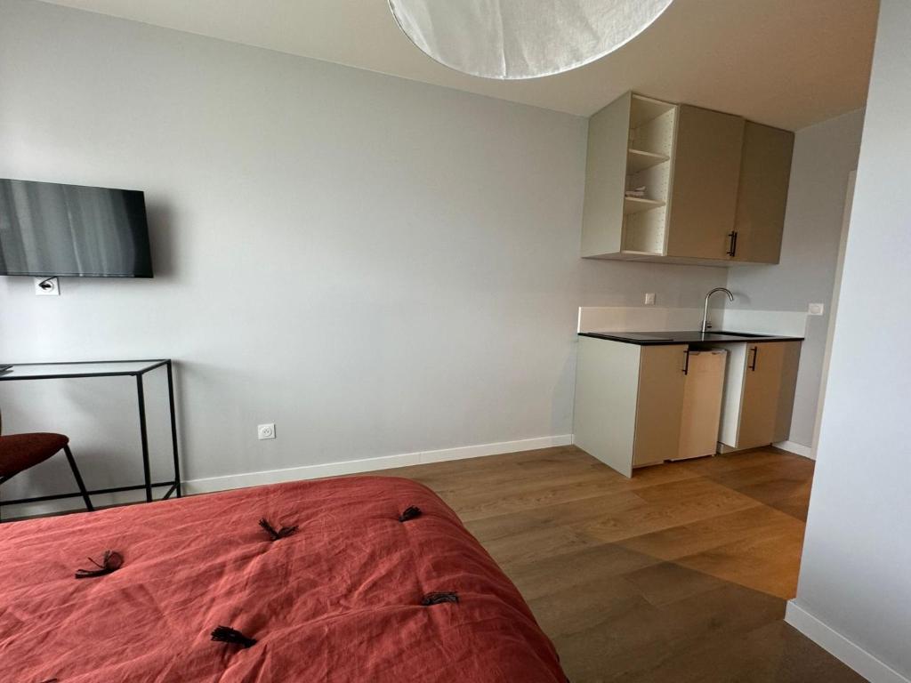 Cet appartement comprend une chambre avec un lit rouge et une cuisine. dans l'établissement M72 Marquer Studio centre ville d'Annemasse, à Annemasse
