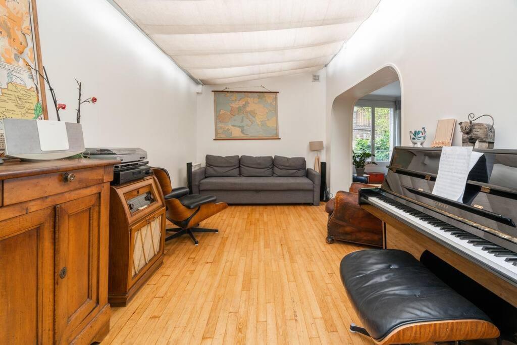un salon avec un piano et un canapé dans l'établissement Charmante Maison au Raincy, à Le Raincy