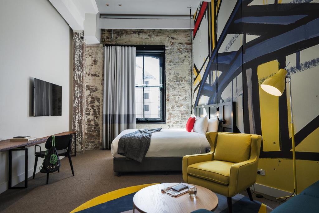 a hotel room with a bed and a yellow chair at The Woolstore 1888 by Ovolo in Sydney