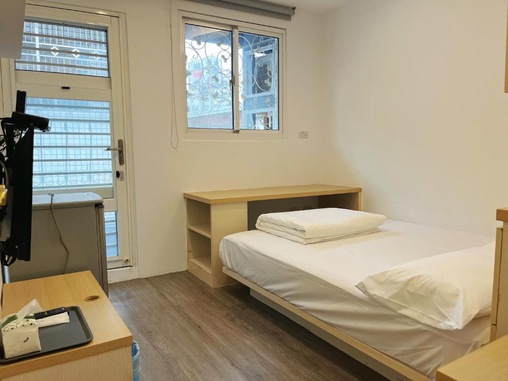 a bedroom with a bed and a desk and windows at Fengjia Jocy House in Taichung