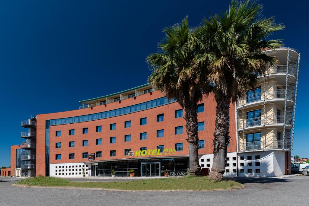 a hotel with two palm trees in front of it at B&B Hotel Pisa in Pisa