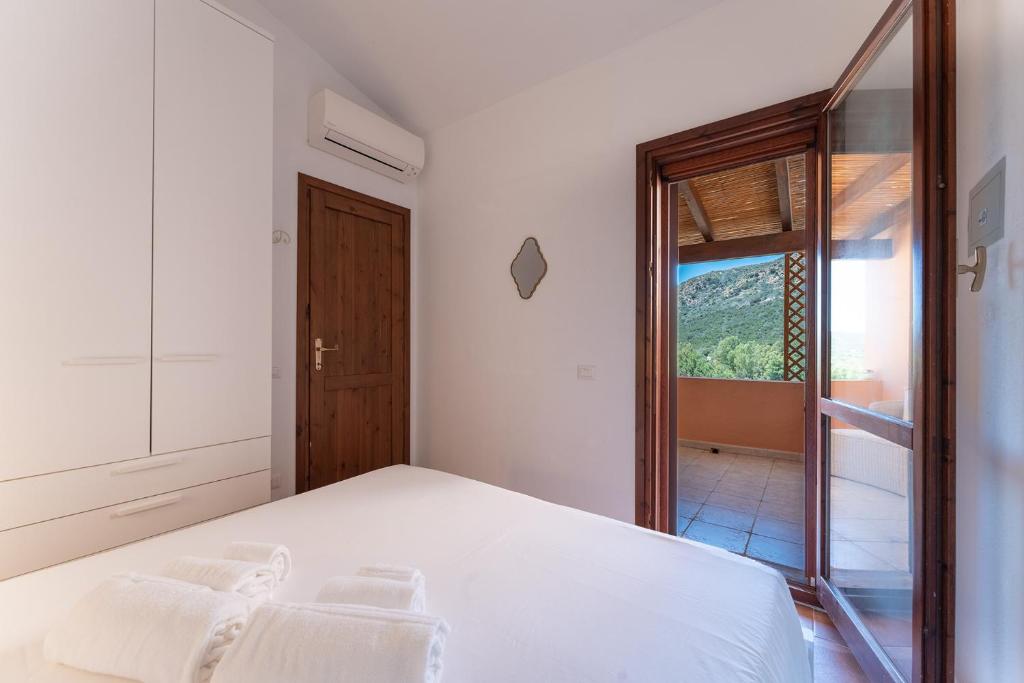 a bedroom with a large white bed and a window at Villa Perdalonga, Vista Mare Sea View Tuerredda in Teulada